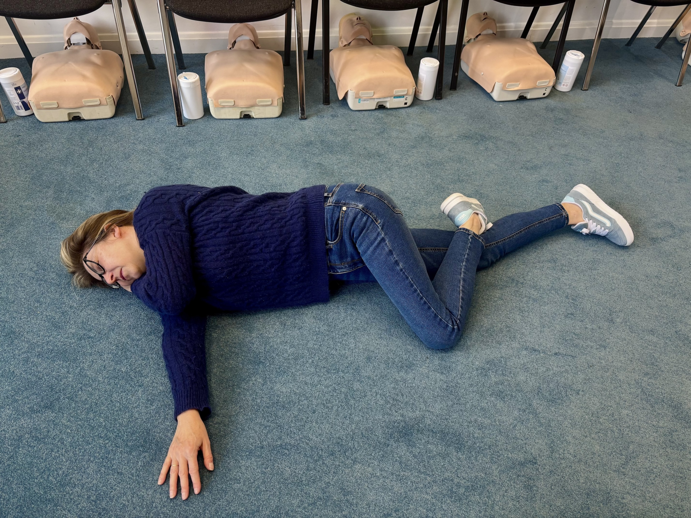 First aid instructor demonstrating how to place a casualty in the recovery position step by step